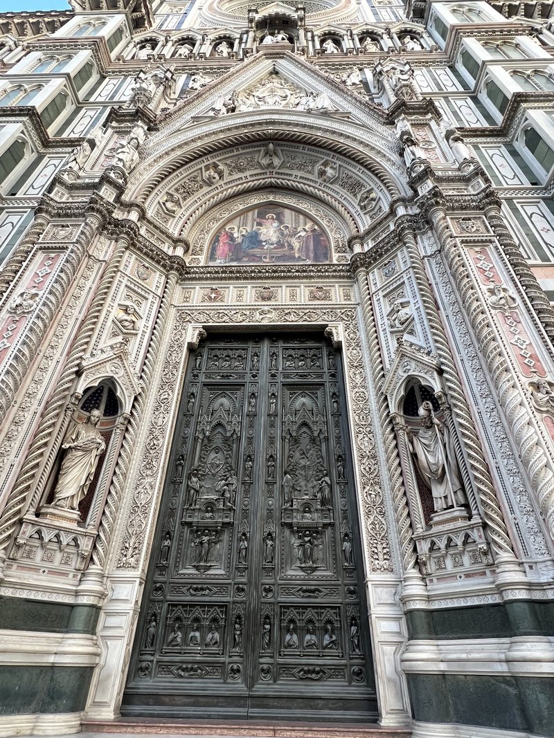 A bronze door between its flanking saints