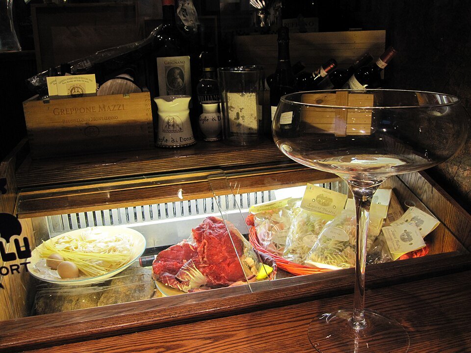 An enoteca counter: cured meat, cheese and a glass of red