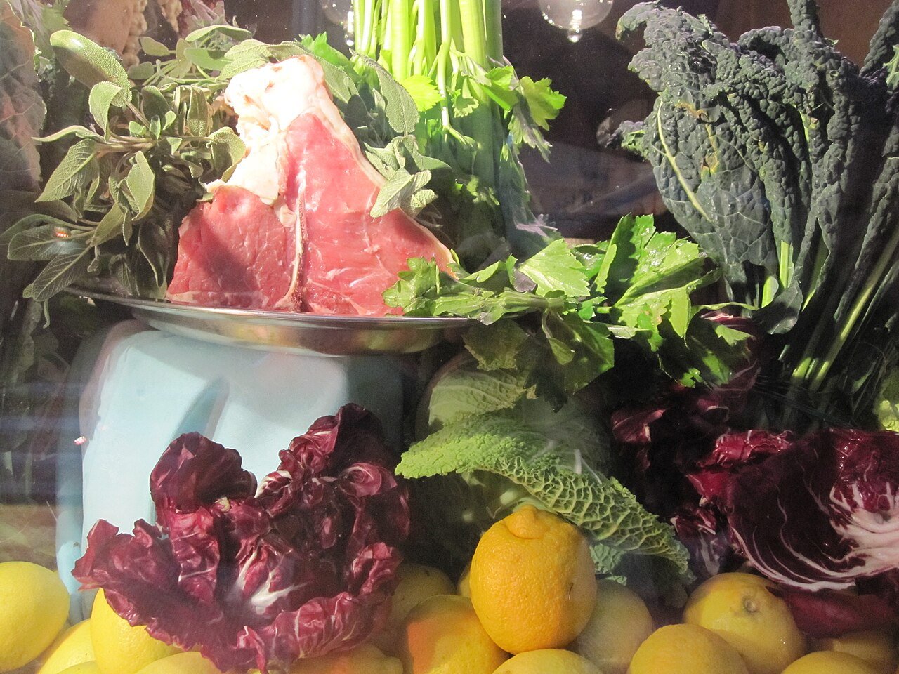 A bistecca in a restaurant window, banked with cavolo nero and lemons